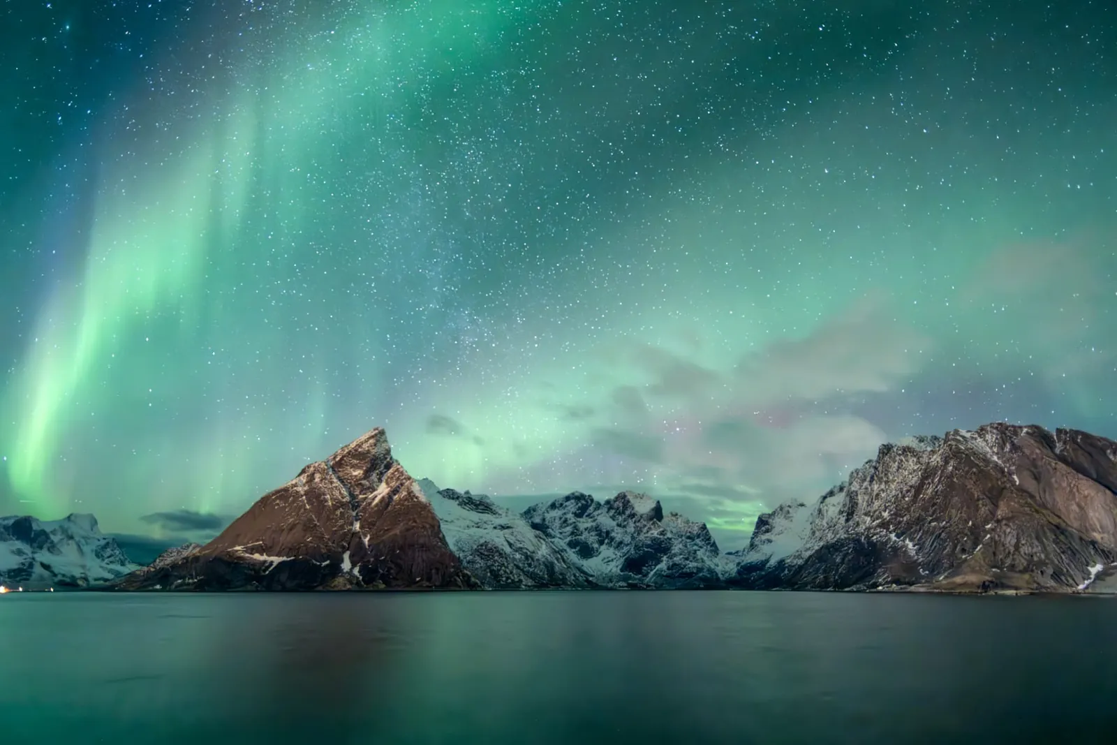 Aurora over snow-covered Lofoten peaks and still water