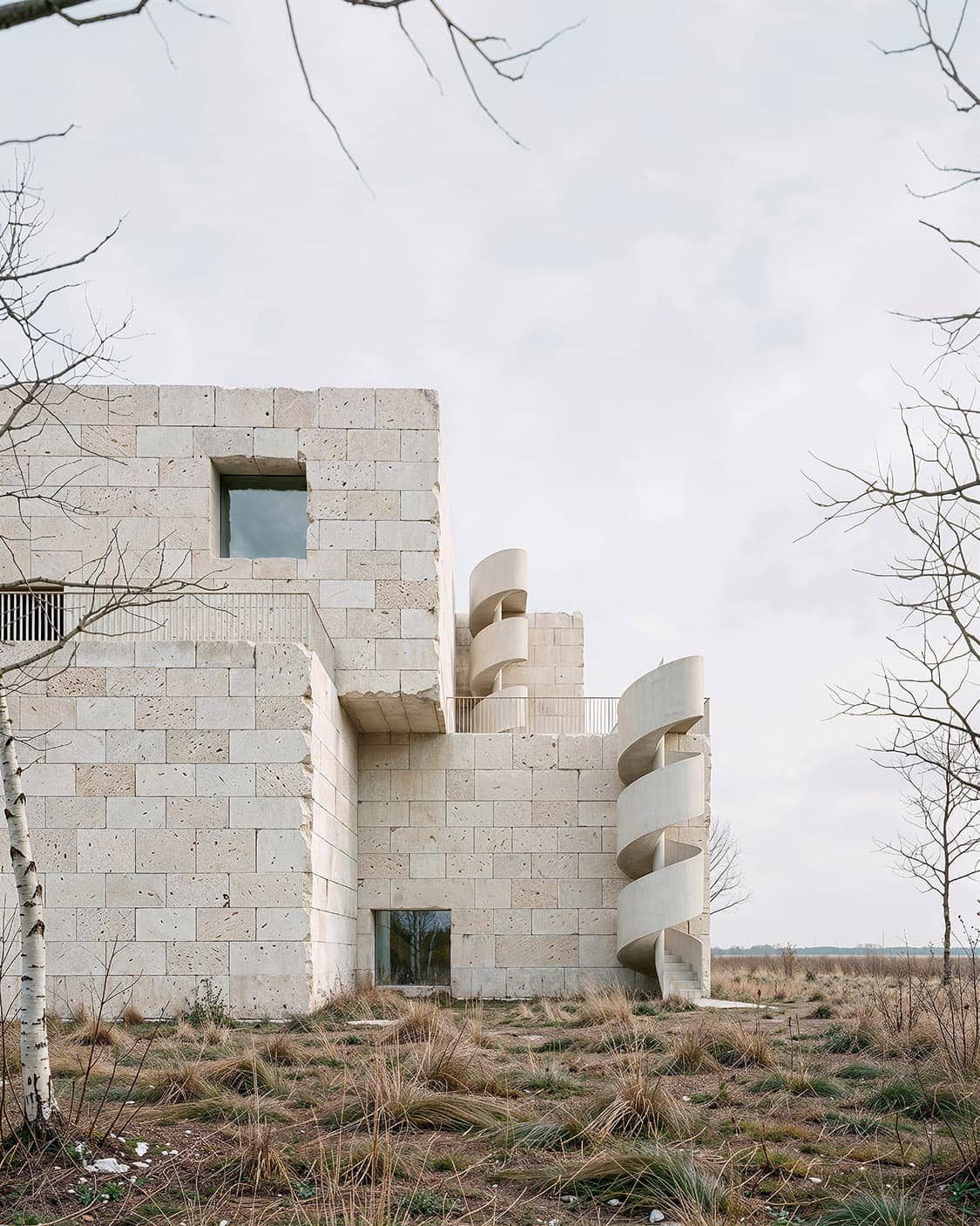 Experimental concrete block house with curved balcony forms in open landscape, visualised by ro01.studio